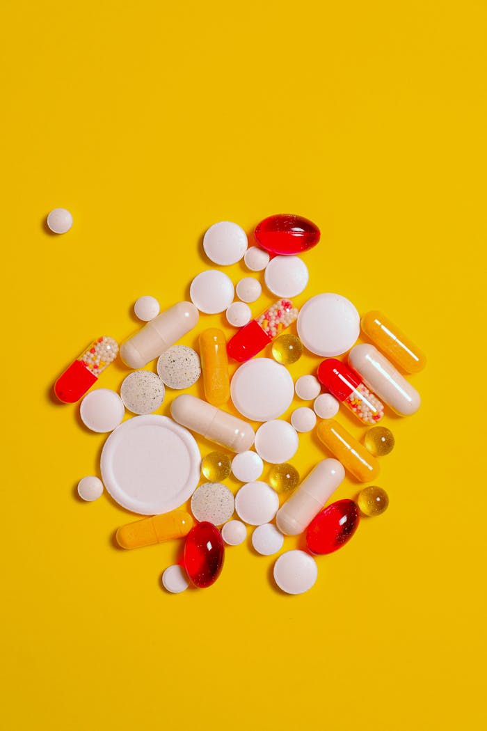 services-02 A collection of diverse tablets and capsules on a vibrant yellow background, symbolizing healthcare and medication.